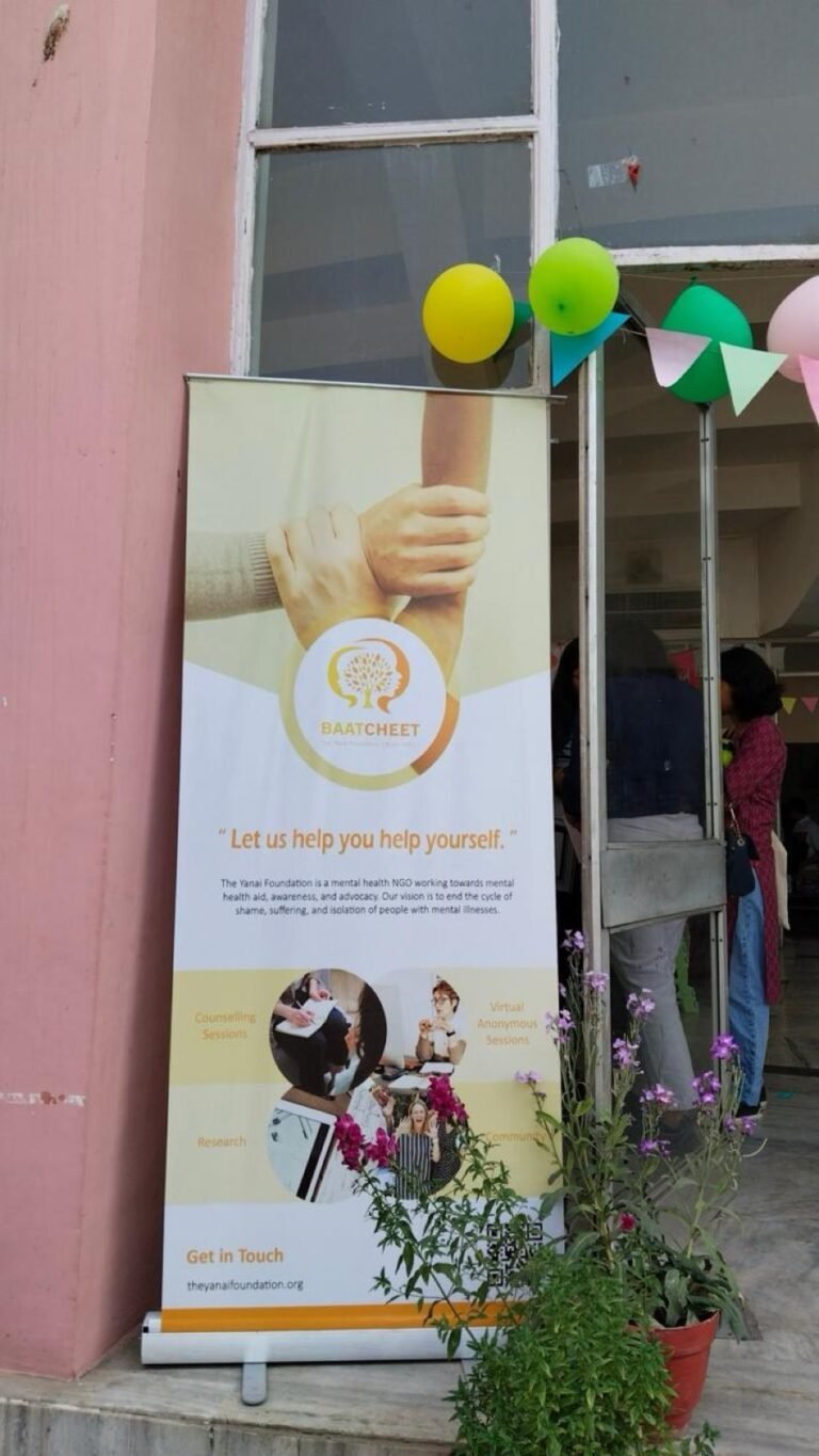 A Baatcheet banner stands at the entrance to a building, decorated with balloons and bunting for an event.